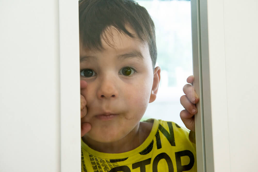 Casa Feliz: Kleiner Junge schaut durch Glastür