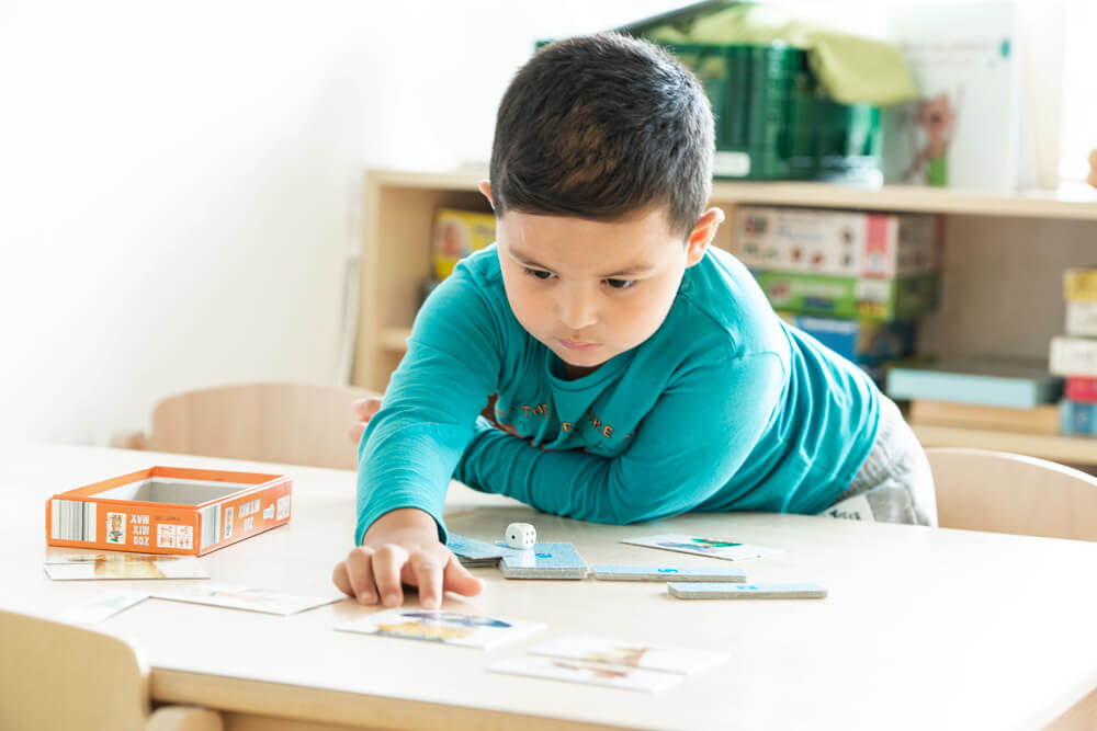 Casa Feliz: Junge spielt am Tisch Memory
